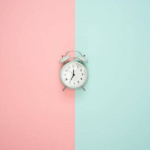 A pink and blue flat lay with an old fashioned duck egg coloured alarm clock 