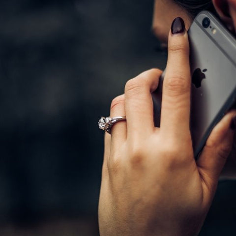 A woman holding a space grey iphone to her ear and talking on the phone