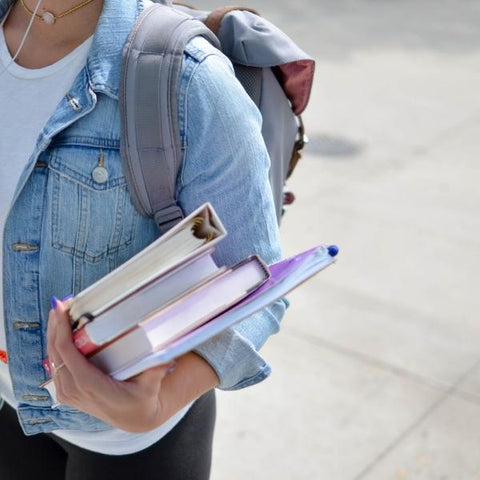 Child holding school books and carrying a rucksack whilst walking back to school