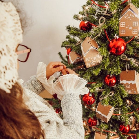 Lady hanging Christmas decorations on Christmas tree 