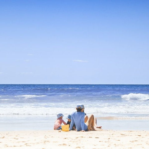 Family sitting on a sandy beach by the sea in the sunshine