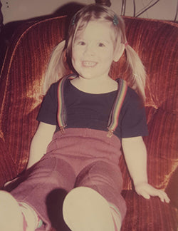 3 year old Kendra in rainbow suspenders on her favorite orange velour chair