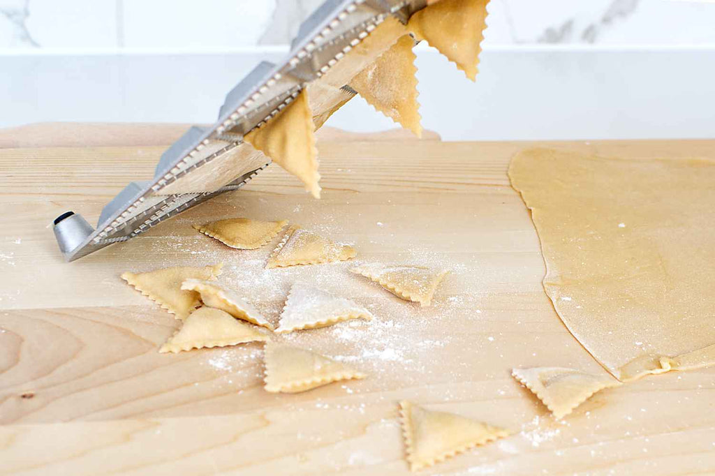 Knocking out ravioli from the tray onto a board.