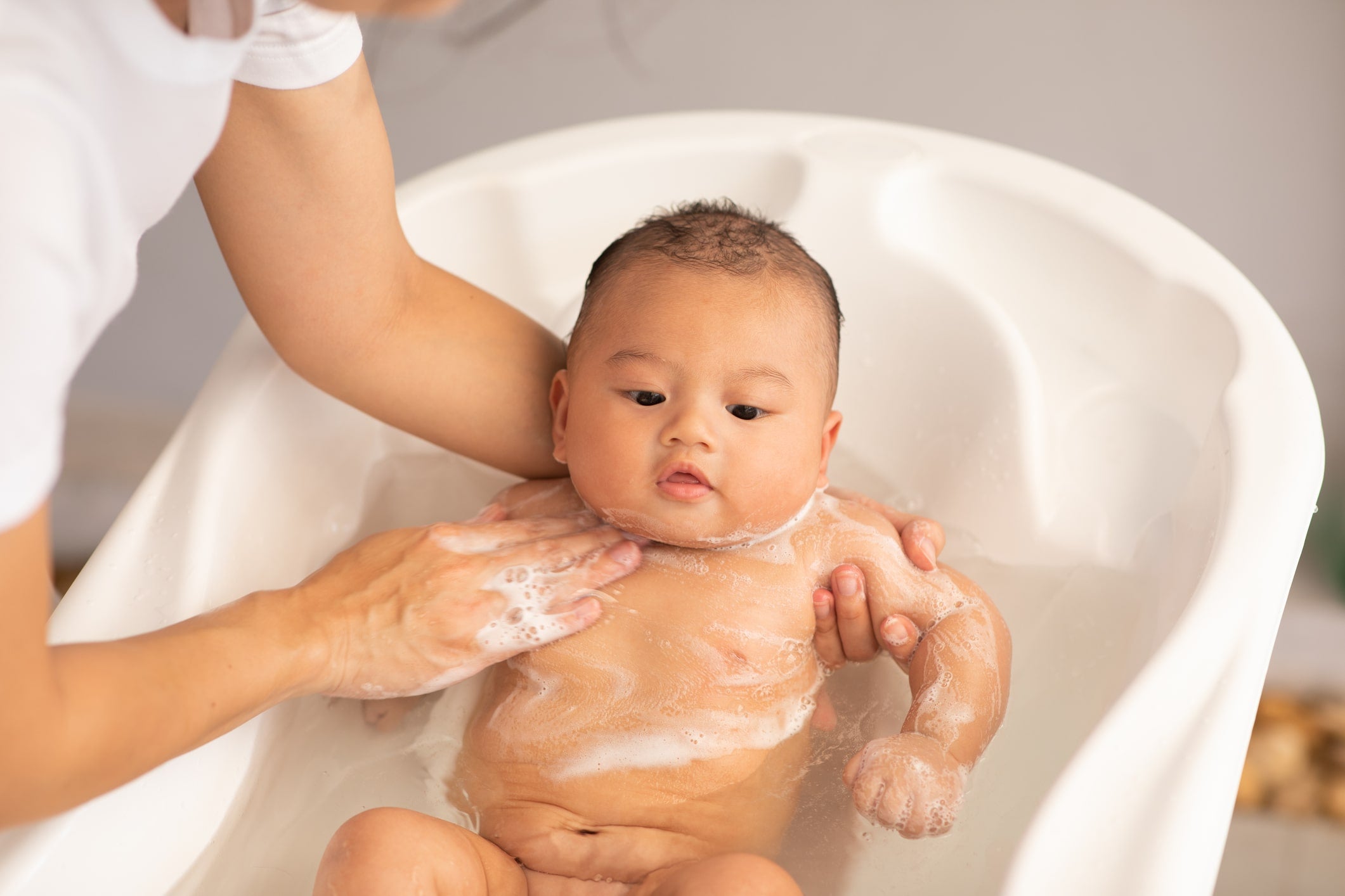 Parent bathing child before being slept in best sleeping position for teething baby