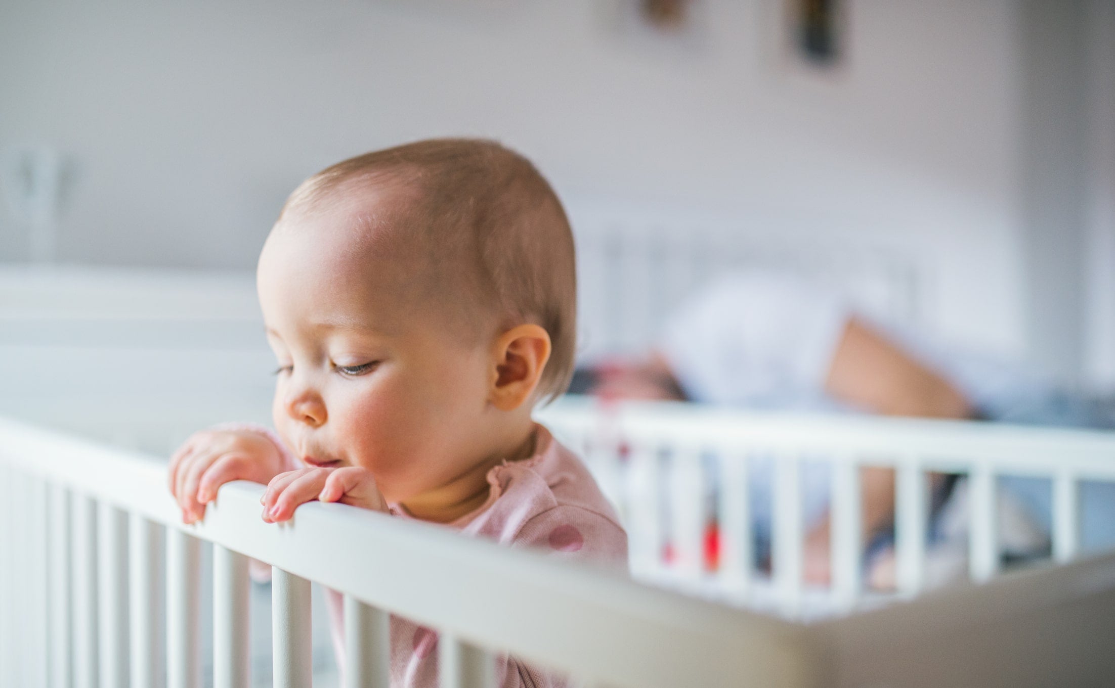 Infant awake while parent wonders how to get baby to sleep in crib