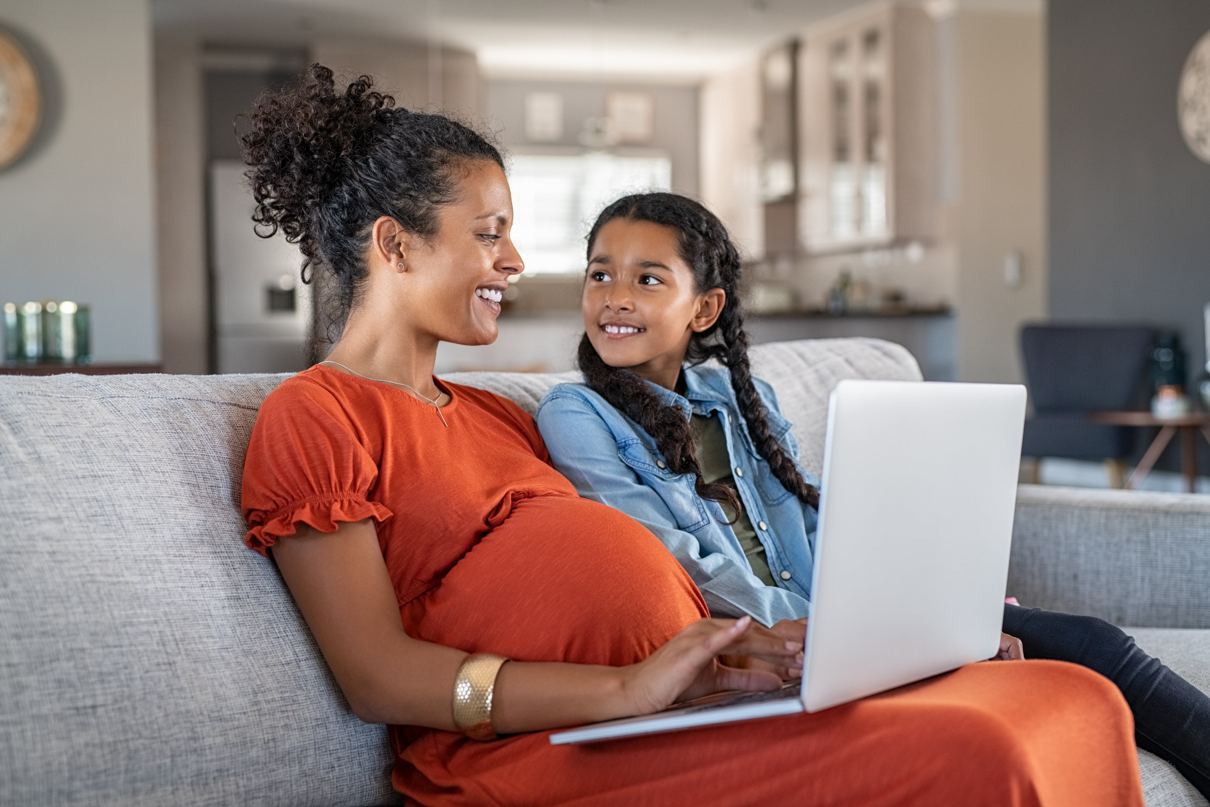 Mother on laptop with daughter searching for a warm bodysuit for baby