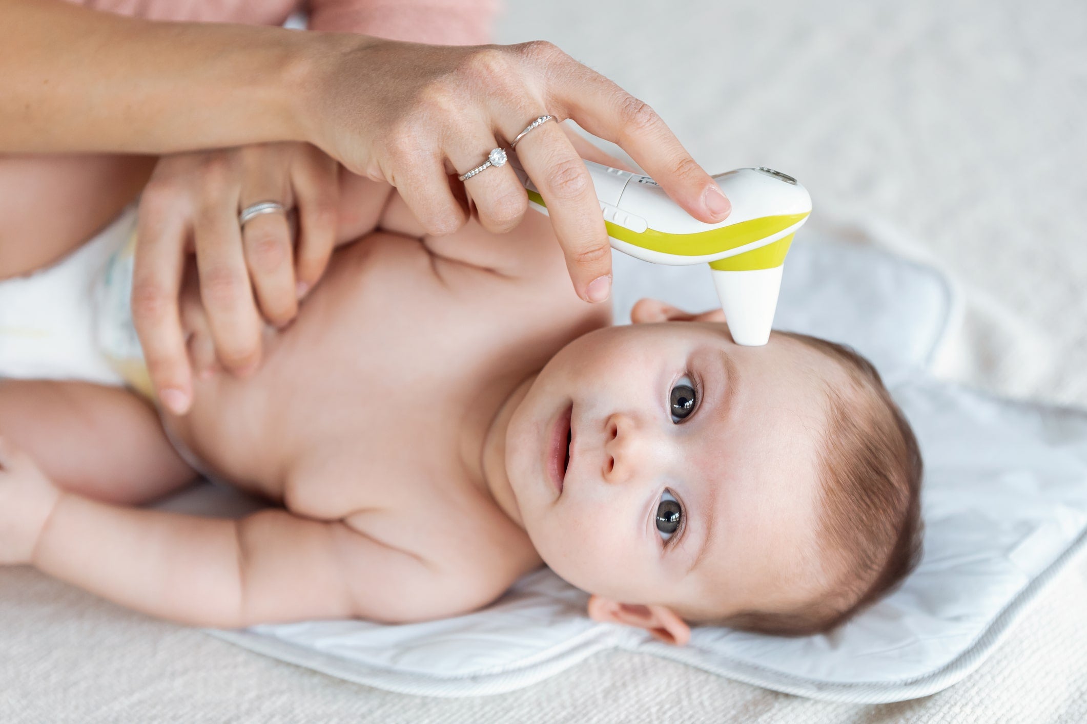 Mother taking temperature for baby sweating at night