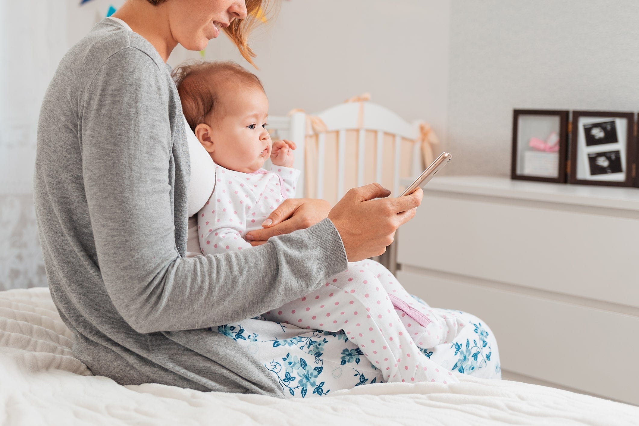 Parent on bed using white noise for baby sleep