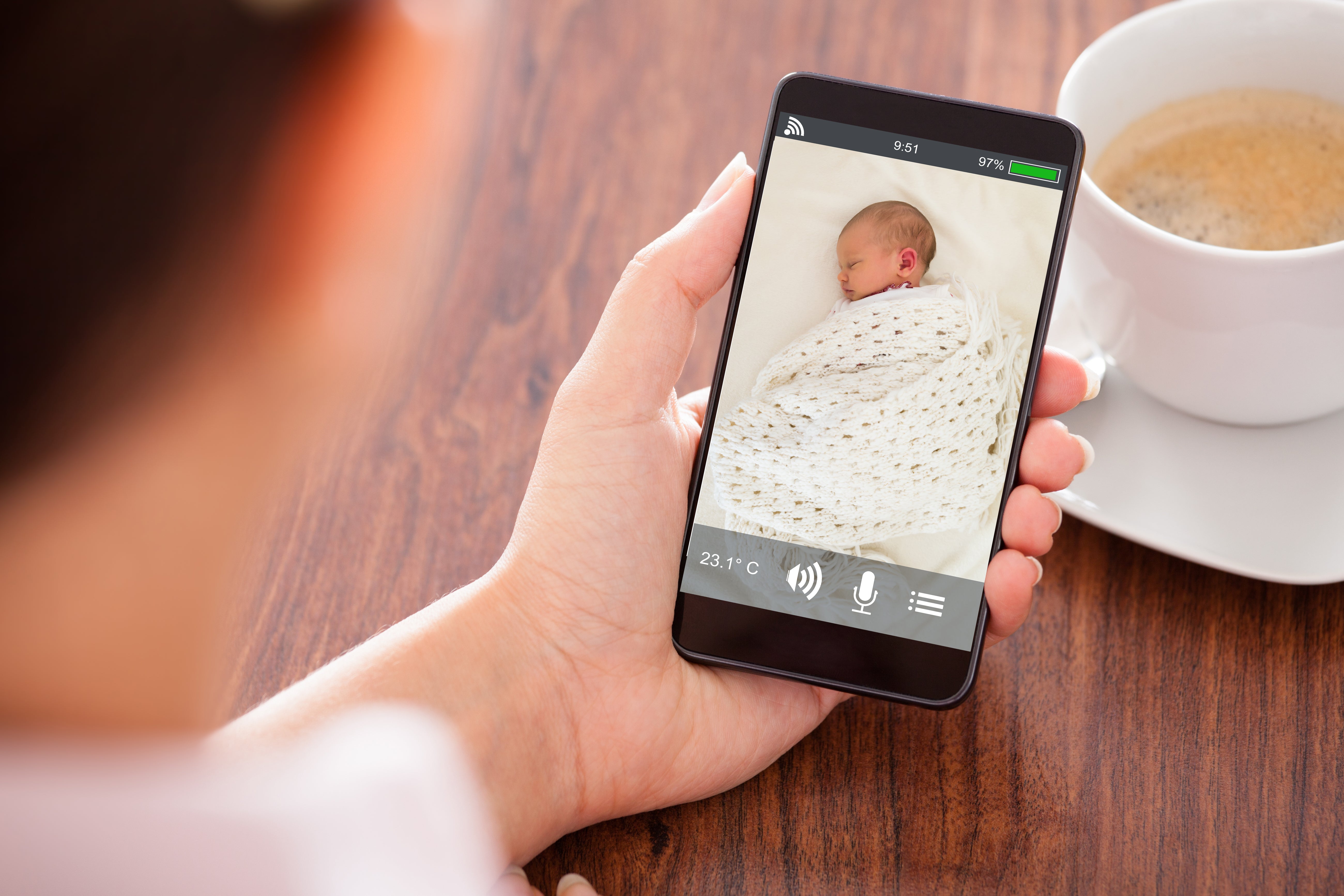 Parent using monitor and phone to ensure safe sleep for baby