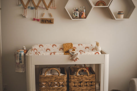 Image of a white change table against a cream wall, filled with nappy changing essentials.