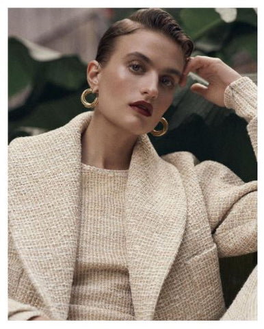 female model wears gold link earrings