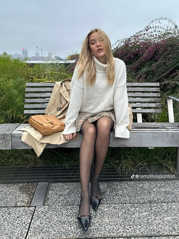 Olivia Ponton poses on bench wearing Ben-Amun earrings and Burberry outfit
