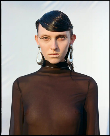 Model wears brown turtleneck and silver Ben-Amun earrings