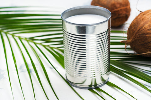 can of coconut milk with 2 coconuts and a green leaf