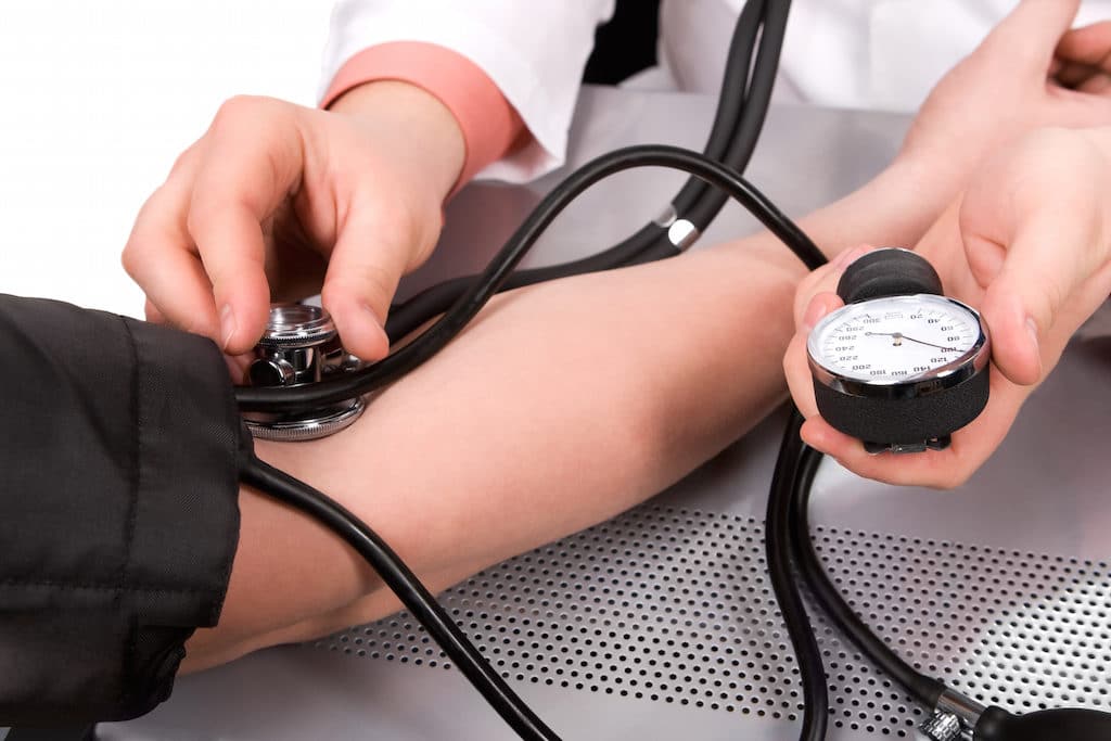 doctor checking blood pressure with stethoscope and sphygmomanometer
