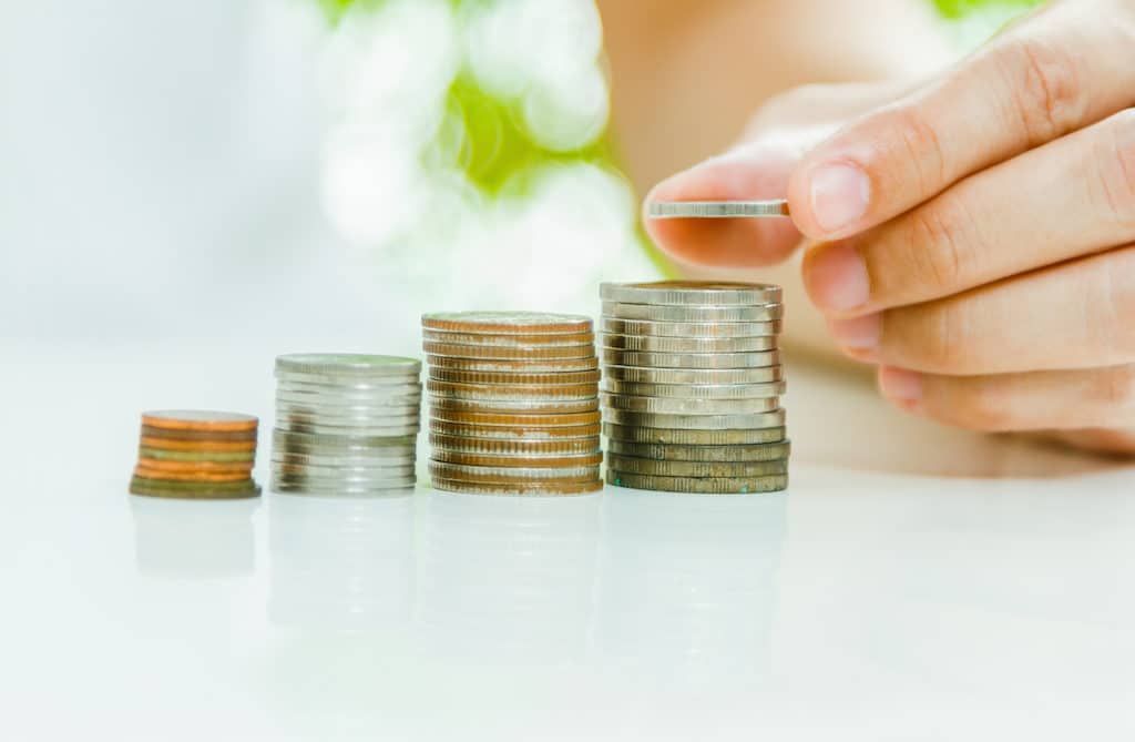 Hand putting coin on coins stack with city background. Savings, Finance , Business Investment Growth Concept,Saving money concept,woman hand putting money coin stack growing business.