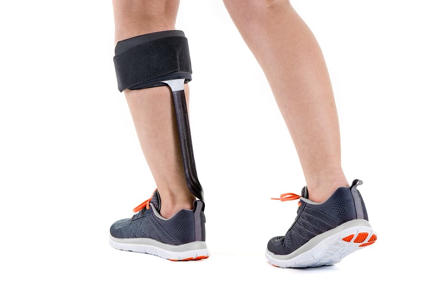 Close Up Rear View of Person in Athletic Sneakers Wearing Support Brace Around Calf Leg Muscle in Studio with White Background
