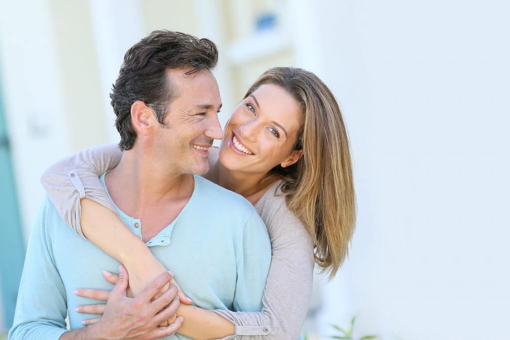 Middle-aged couple embracing in front of house