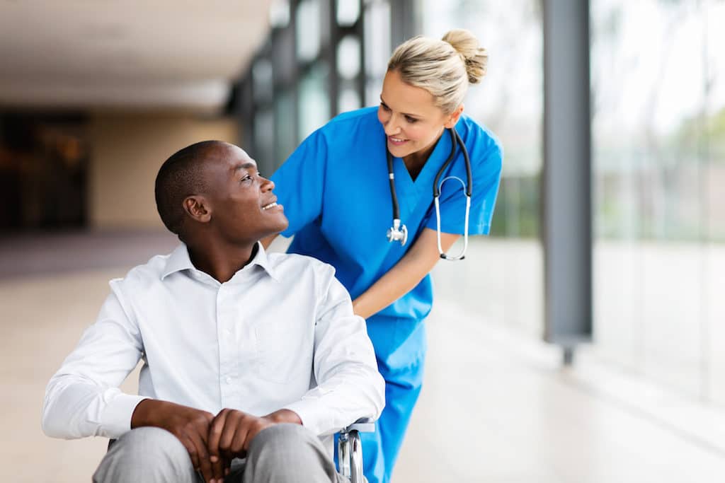 caring female nurse talking to disabled patient in hospital