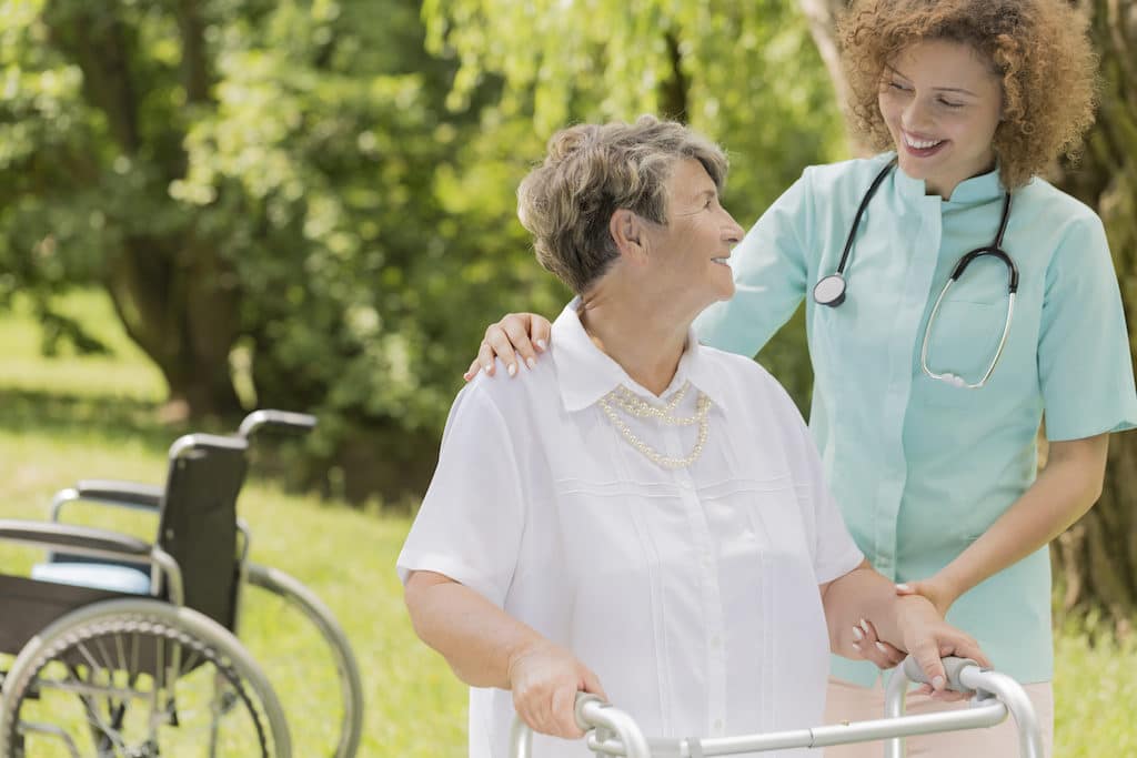 Cropped shot of a smiling caregiver assisting a senior woman in the park