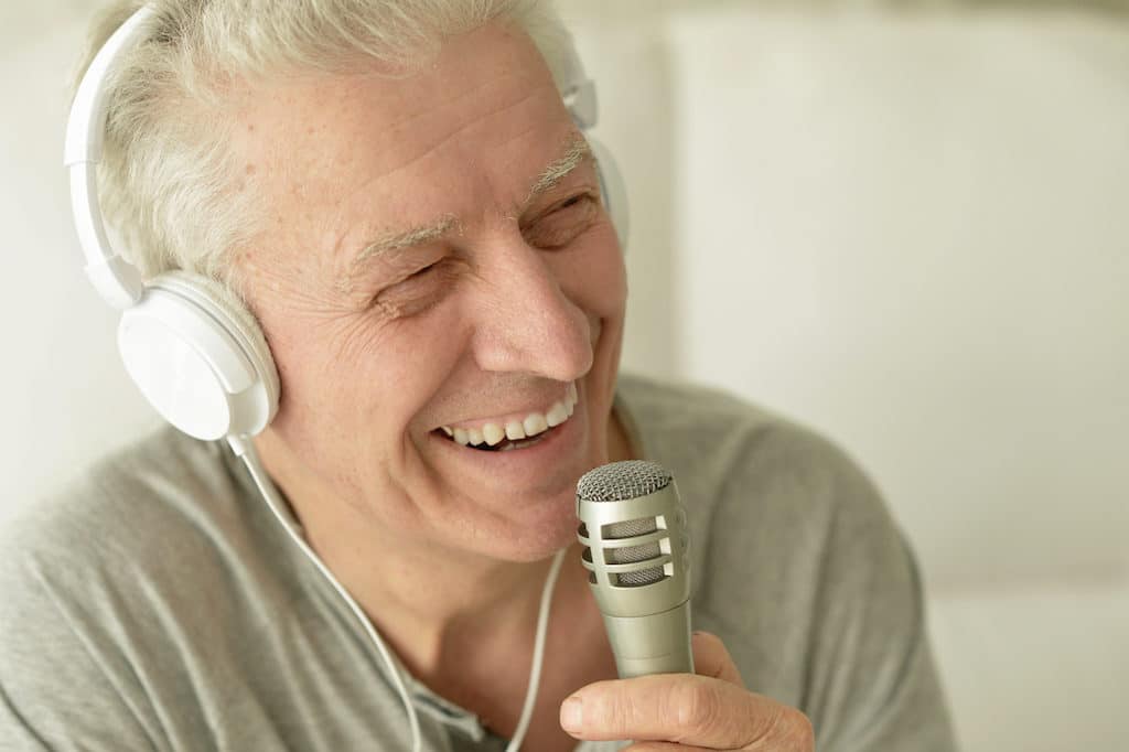 Senior man singing into microphone in headphones