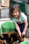 a young girl using a garden hoe to dig in the soil of a vertical planter