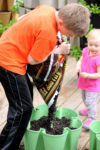 a boy pouring soil at the base of a vertical planter
