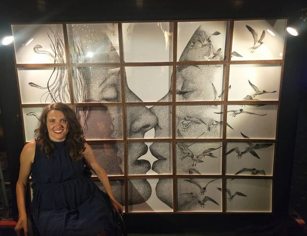 Photograph of Cobie sitting in front of her artwork at the RAW Showcase