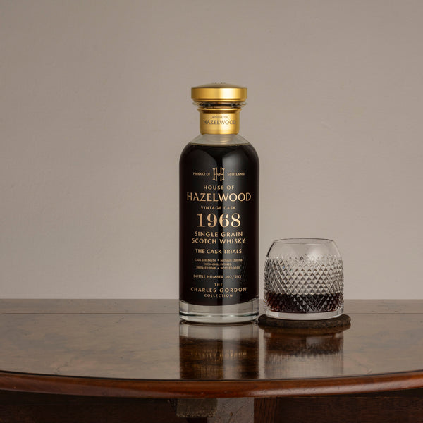 A bottle of The Cask Trials with a pour of the whisky in a crystal glass