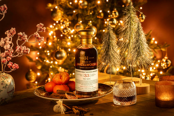 The Tops Scotch Whisky sits on a table surrounded by Christmas tree decorations and frosted berries.
