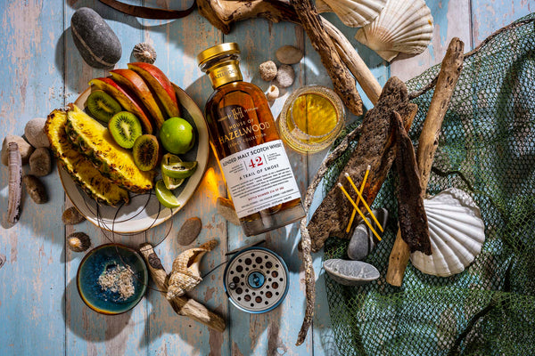 A bottle of A Trail of Smoke Island Whisky surrounded by fishing nets and maritime tools