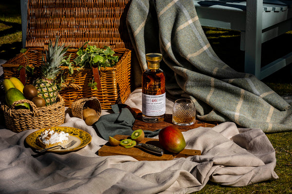 A bottle of the Spirit of Scotland whisky and food pairings on a picnic blanket