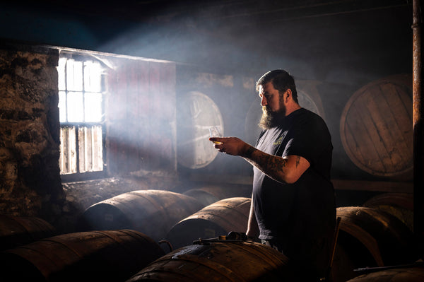 A warehouseman inspects a glass of whisky straight from the cask