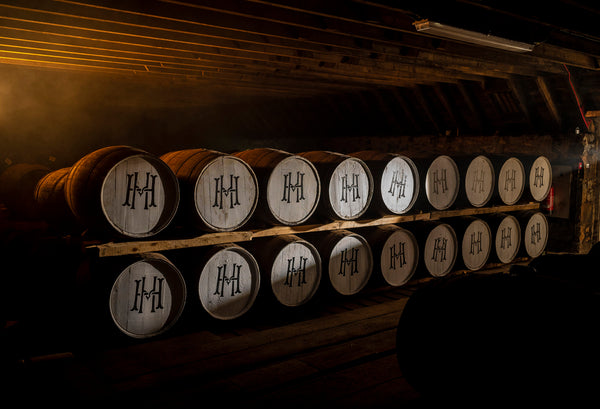 A row of House of Hazelwood whisky casks in a warehouse.