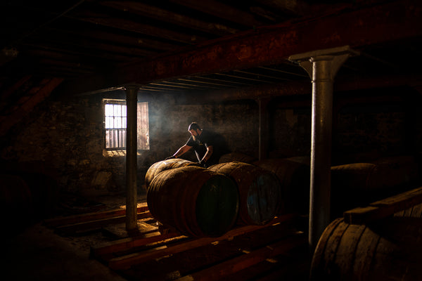 George rolls casks across a warehouse floor