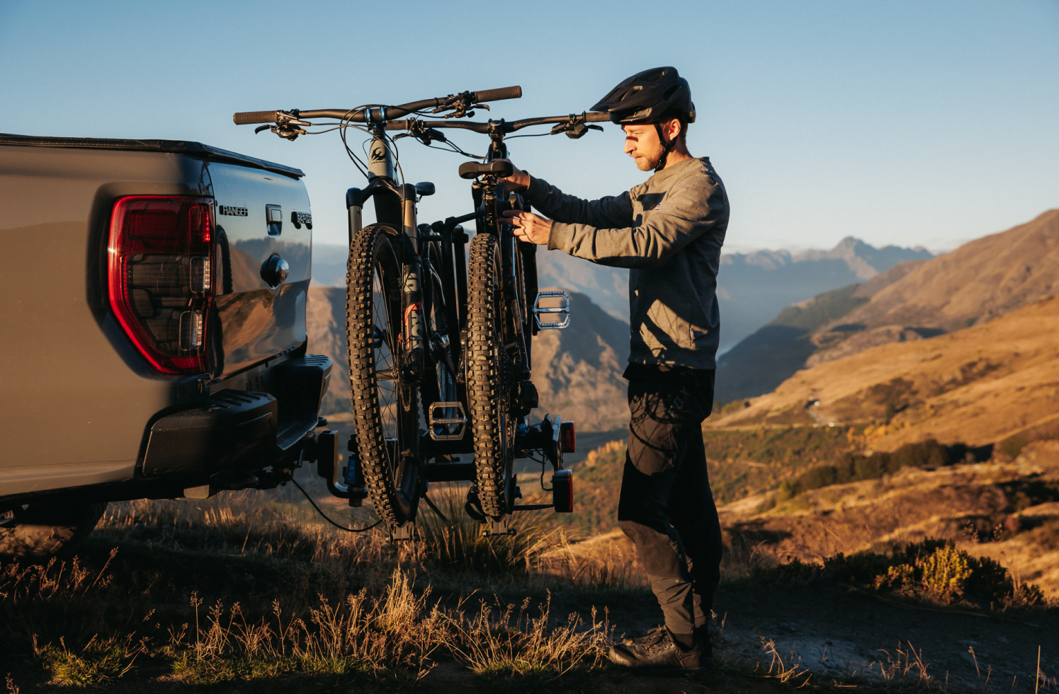 A man is installing his emtb onto an Ezigrip E-Rack 2 that is mounted to his ute.