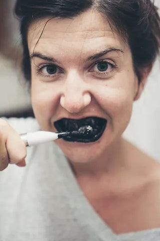 woman brushing teeth with charcoal