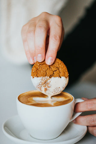 man dunking coookit in to latte