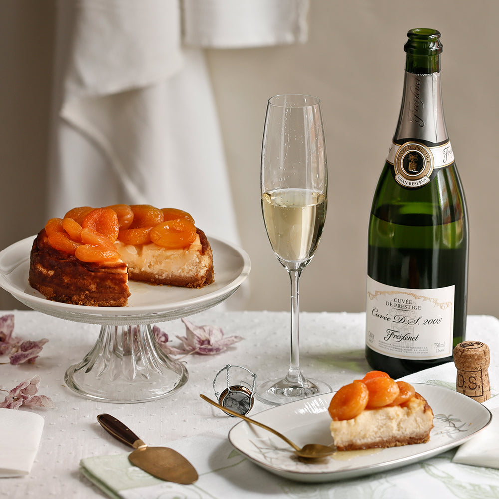 Escena donde se muestra una tarta con una copa y una botella de cava Cuvée DS