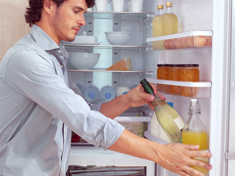 Hombre metiendo una botella de vino al frigorifico