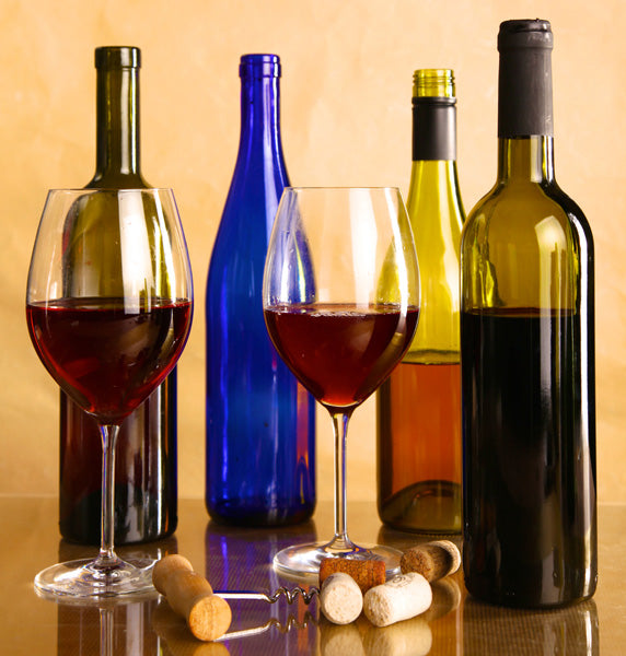 Escena con cuatro botellas de vino de diferente color y dos copas de vino