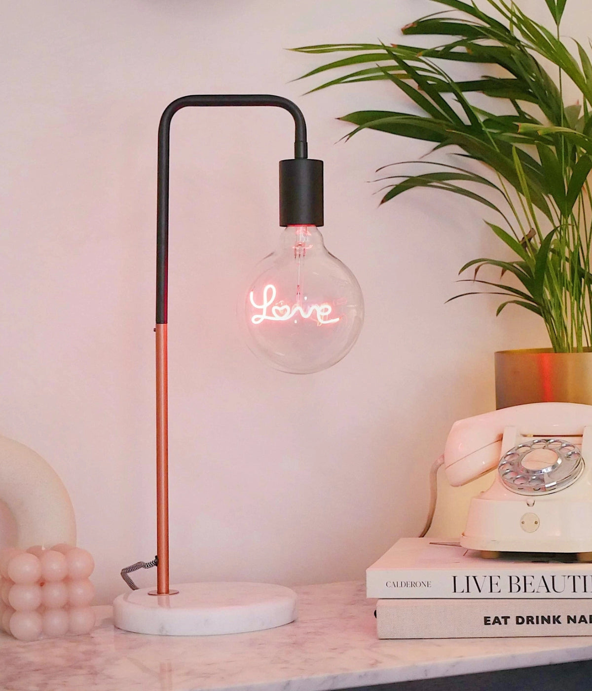Tavolo in marmo con con libri e telefono, lampada da tavolo, base marmo bianco, stelo rame e nero.