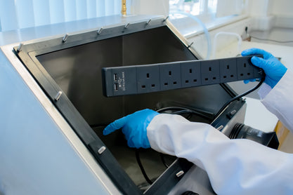 Multi-socket extension power supply being placed into the Ossila Laboratory Glove Box
