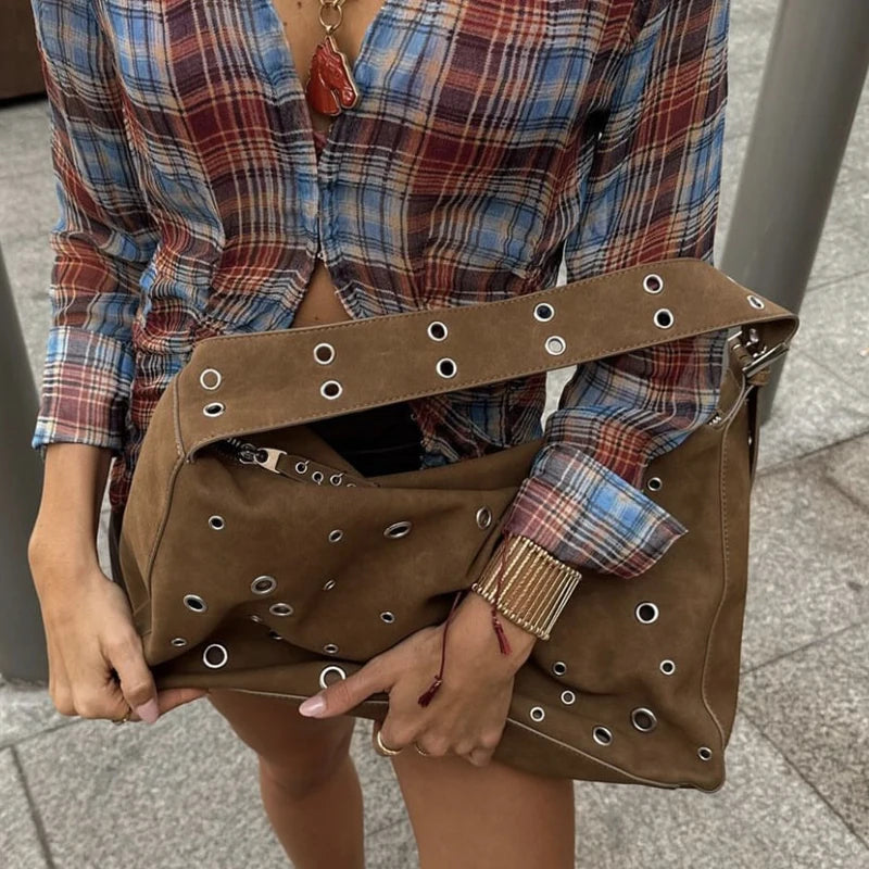 Large suede bag with silver eyelets worn with a winter coat