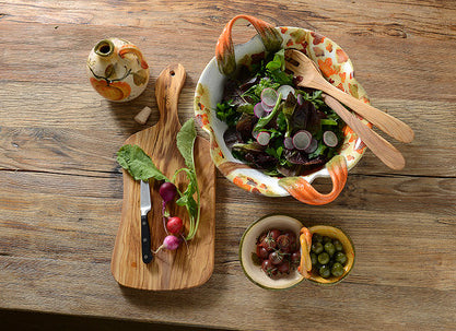 salad set with ceramic bowl, olives, wooden cutting board and olive oil