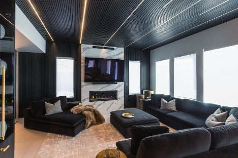 Black couches in a black living room with light fixtures in the ceiling