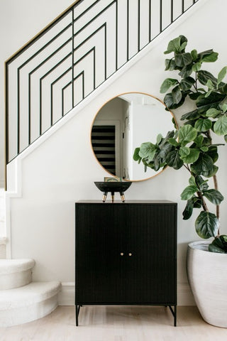 Round mirror on wall above black cabinet