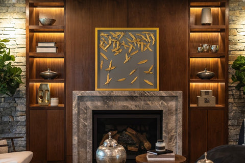 Wood panel with lit shelves surrounding granite fireplace and art piece hanging above