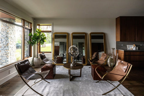 Living room with brown leather chairs, art centerpiece, and vanity mirrors lined up against back wall