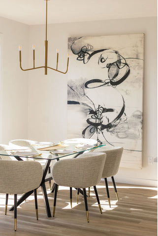 Large black and white painting hanging on dining room wall adjacent to dining table